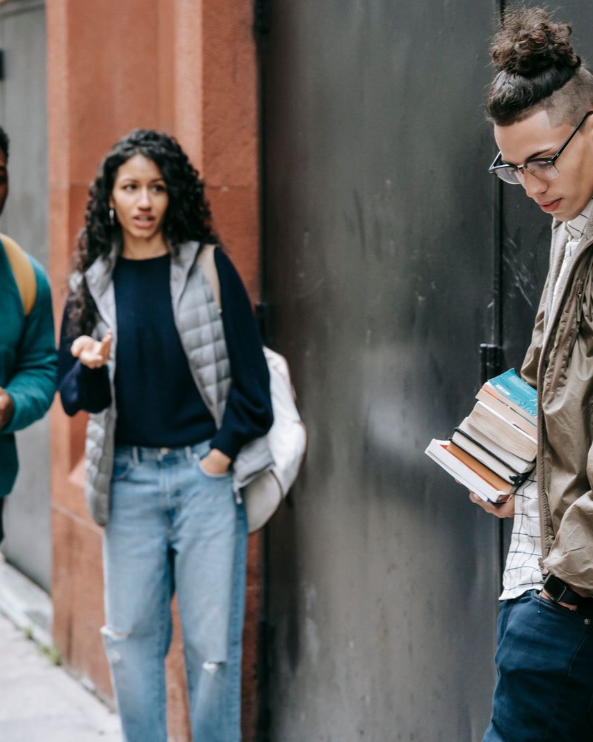 A diverse group of students with books and backpacks on a city street