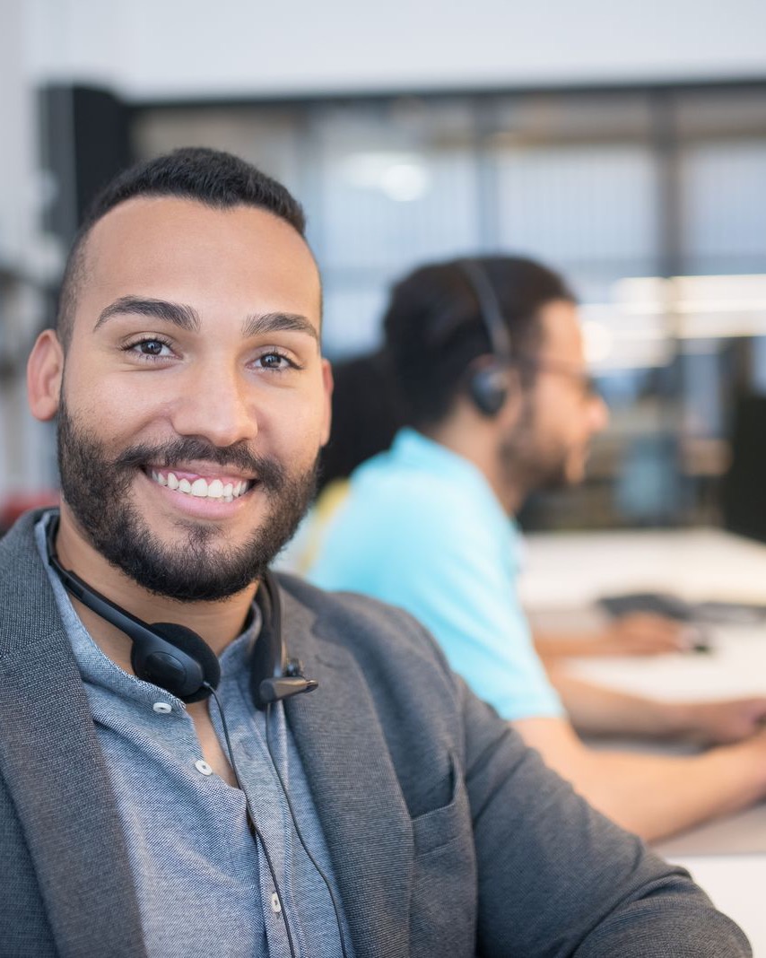A friendly support team member smiling while wearing a headset in an office