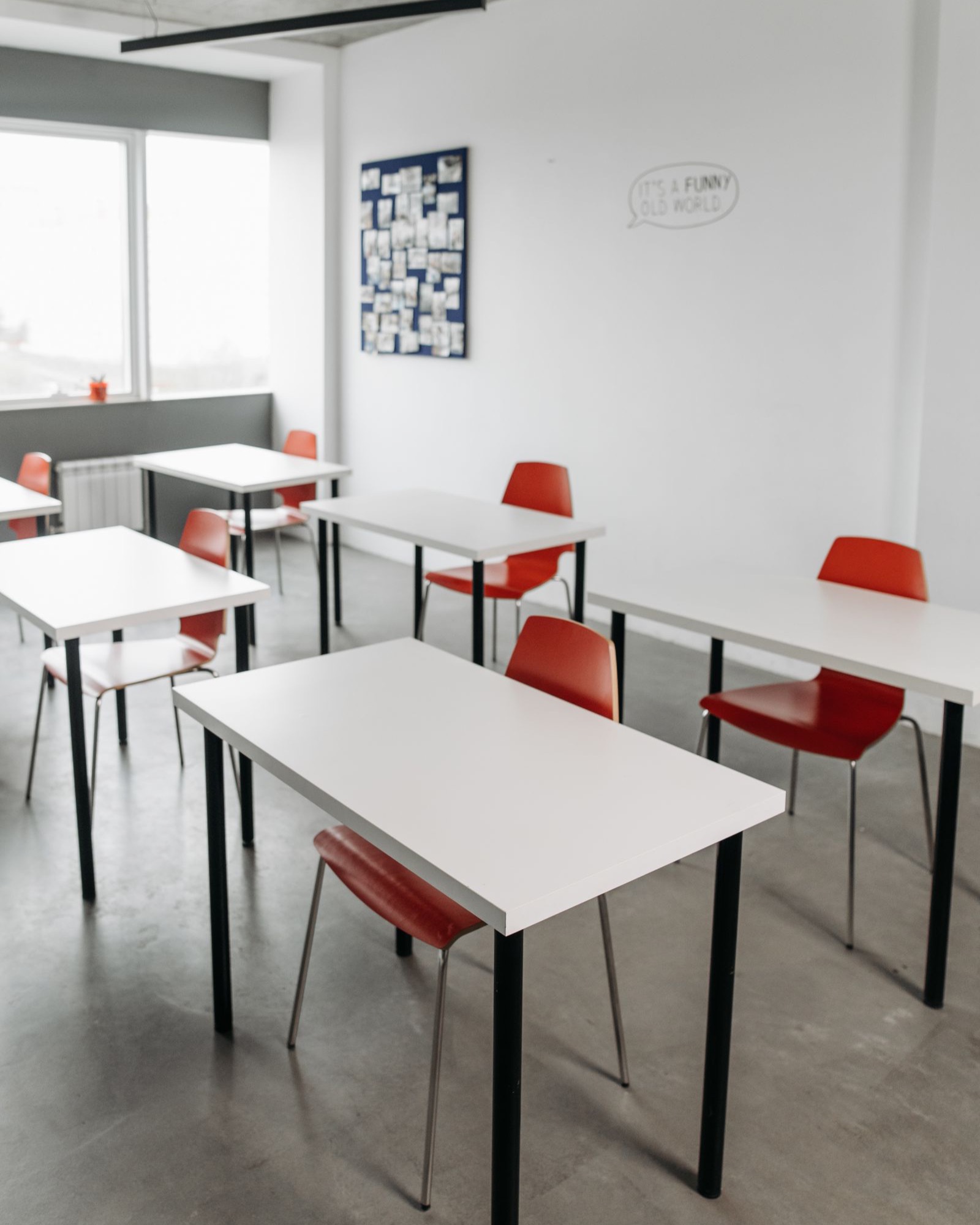 A bright, modern classroom with white desks and red chairs