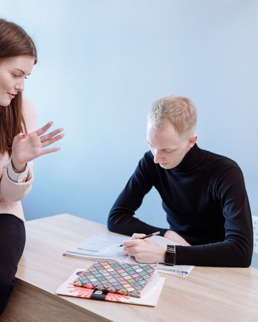 A tutor guiding a student one-on-one at a desk with workbooks